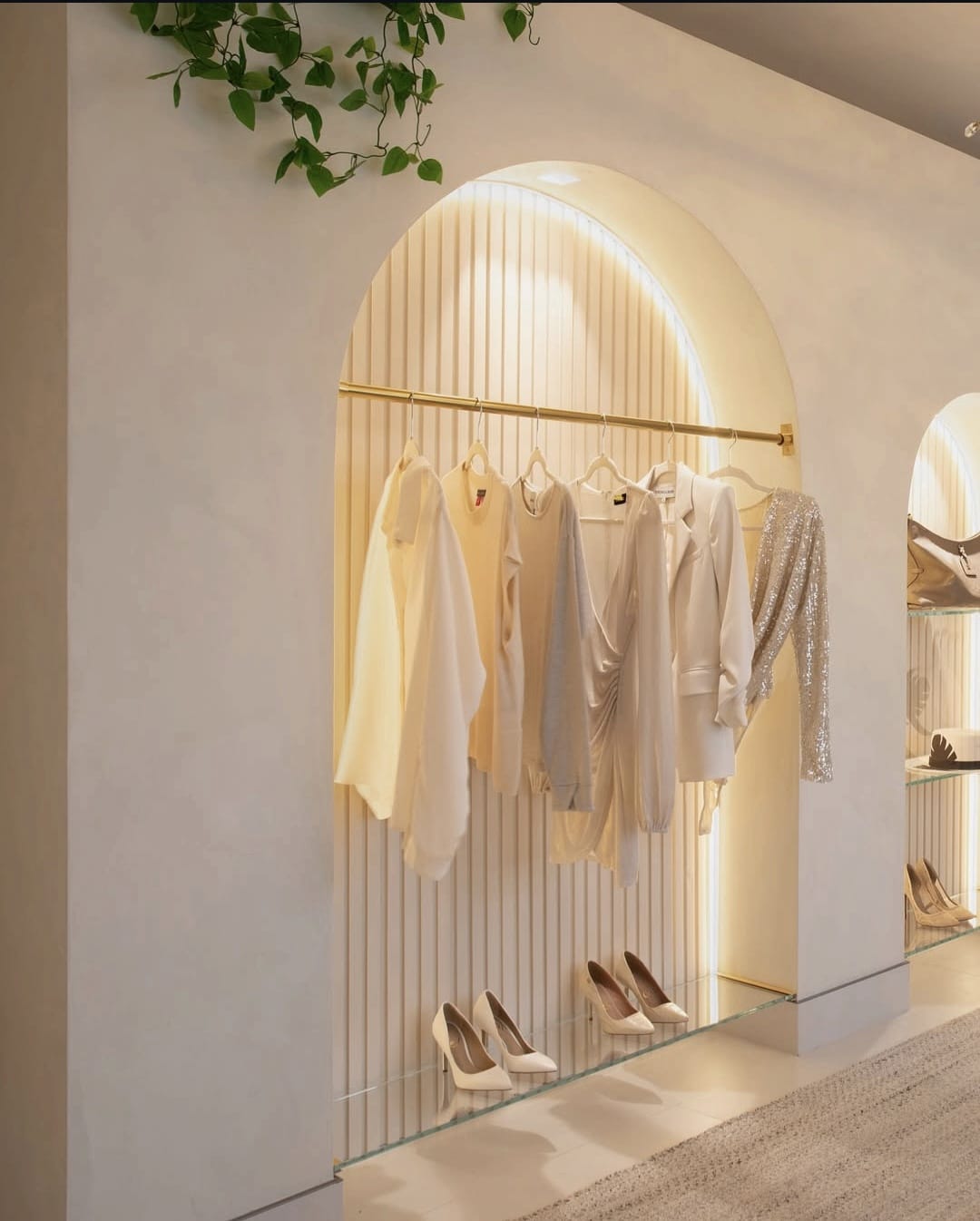 Arched wall niche with warm perimeter LED glow over a fluted backdrop and garment rail.